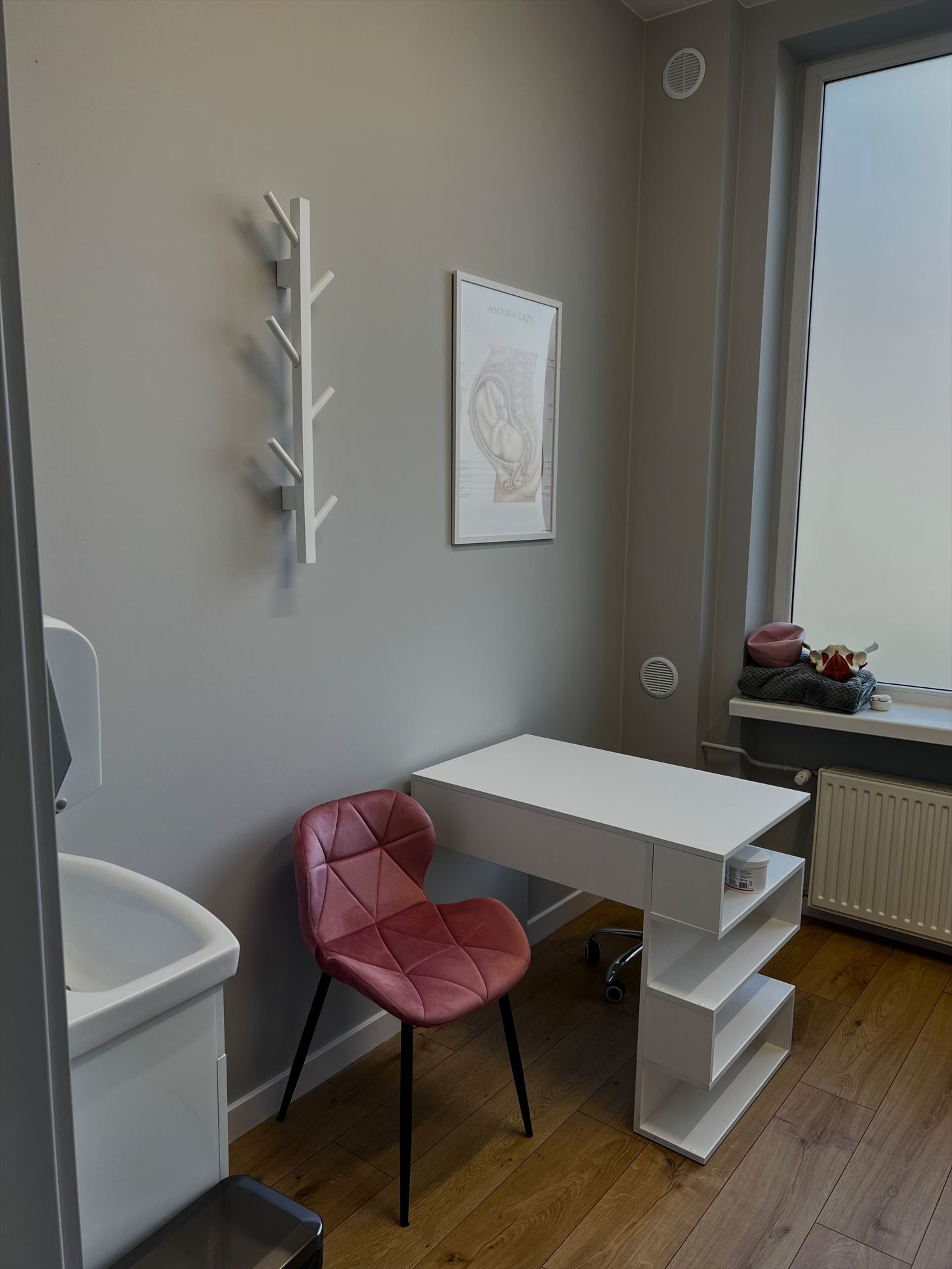 Gabinet konsultacyjny z biurkiem i różowym krzesłem