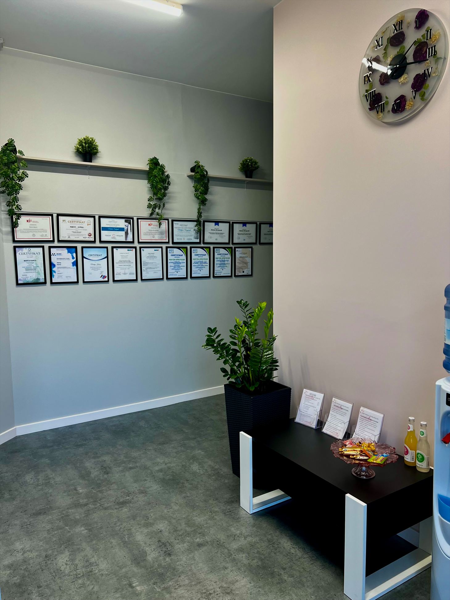 Poczekalnia z ławką, roślinami i ścianą z dyplomami